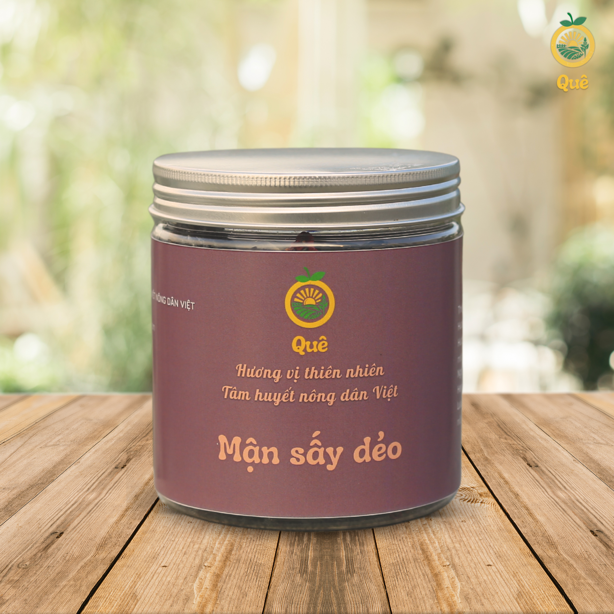 Hũ mận sấy dẻo thương hiệu Quê đặt trên nền gỗ, có slogan 'Hương vị thiên nhiên, Tâm huyết nông dân Việt'