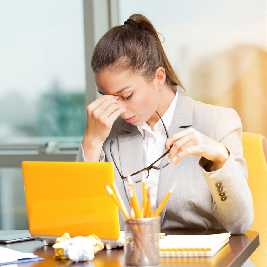 Nhân viên văn phòng trông mệt mỏi khi làm việc, chống tay lên trán và có vẻ căng thẳng